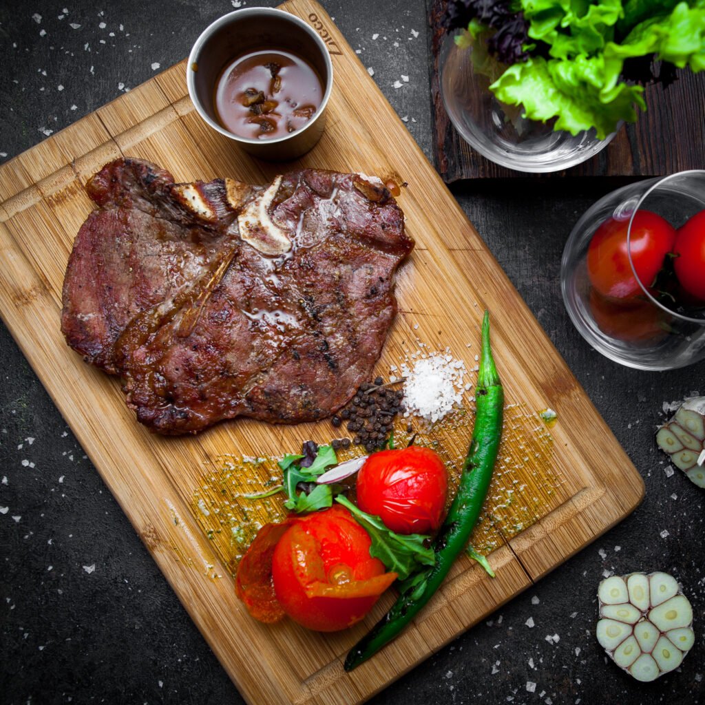 Top view steak with tomato and paper in steak board on dark background